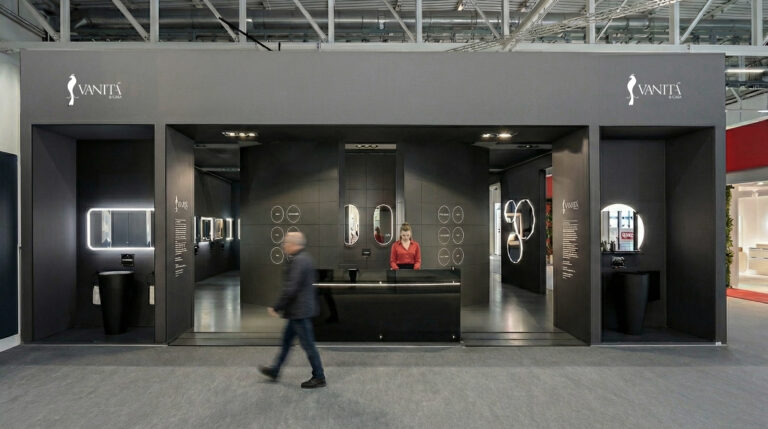 Vista frontale dello stand Vanità & Casa a ISH 2025, con volume monolitico scuro, aperture espositive e prodotti illuminati all’interno.