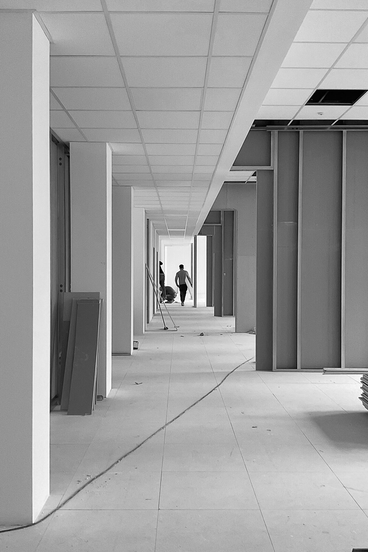 Vista prospettica del cantiere degli uffici Terumo Neuro MicroVention, con strutture delle partizioni interne e controsoffitto in montaggio lungo il corridoio principale.