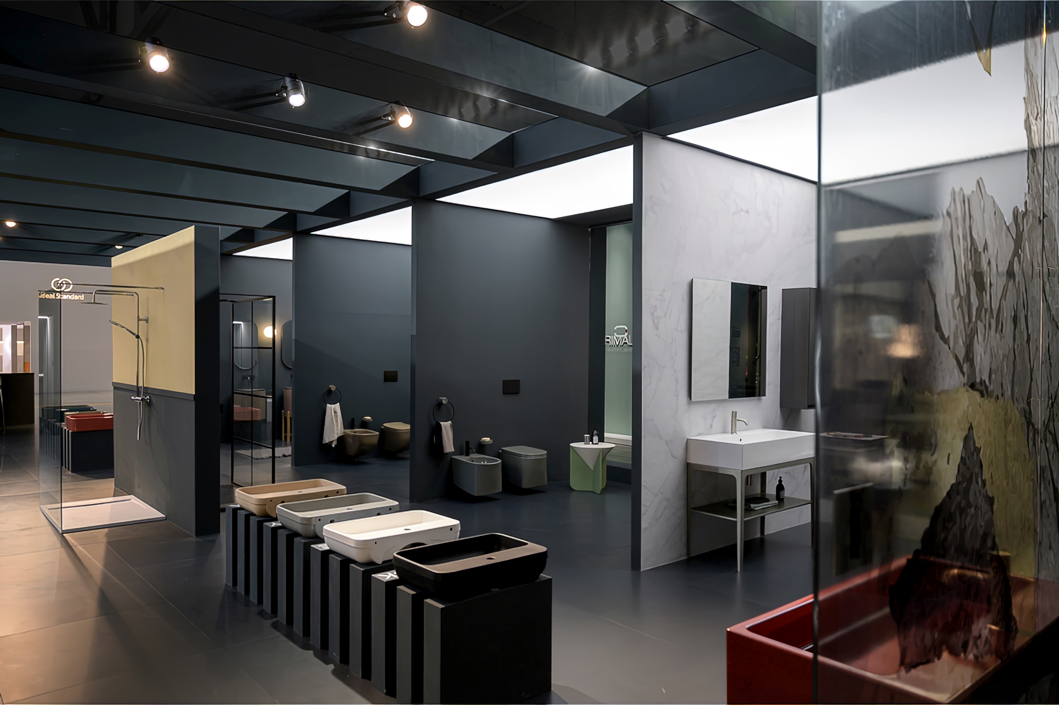 Vista dei box espositivi interni verso l’uscita dello stand Gruppo Colamedici al Salone del Bagno 2022, con percorso espositivo scandito da volumi e luce.