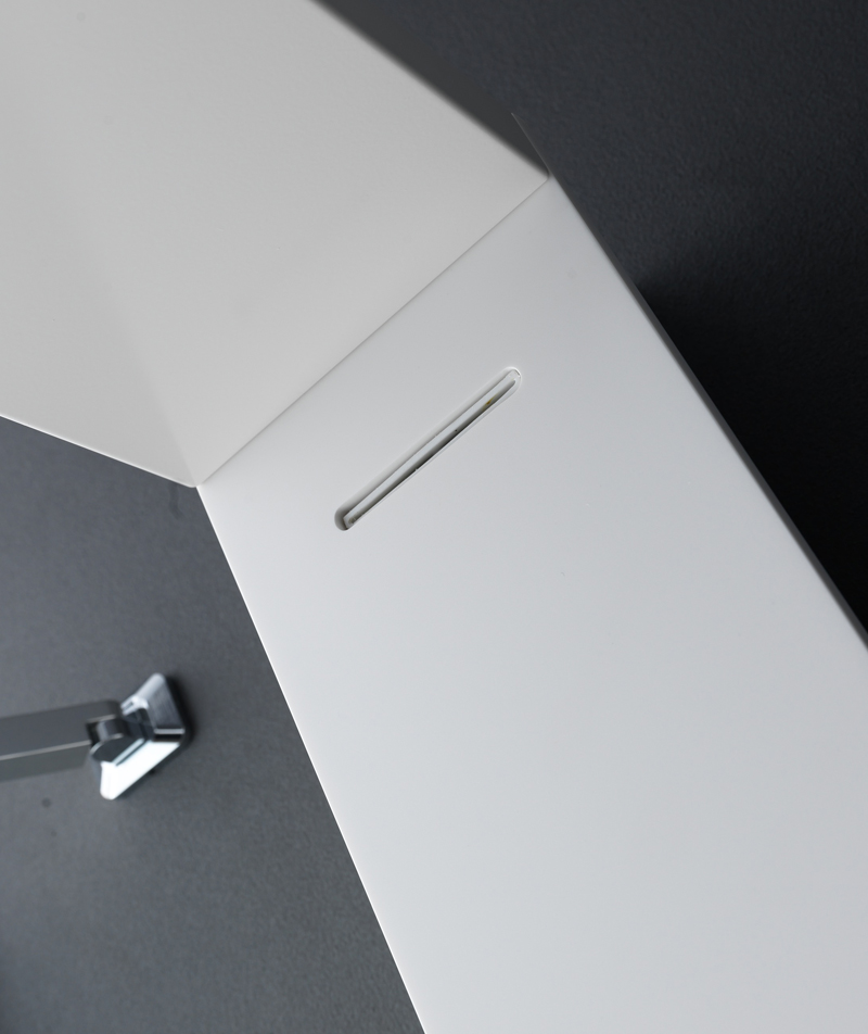 Albatros System: dettaglio del corpo doccia bianco con geometria sfaccettata e fessura lineare della doccia a cascata su parete grigio scuro.