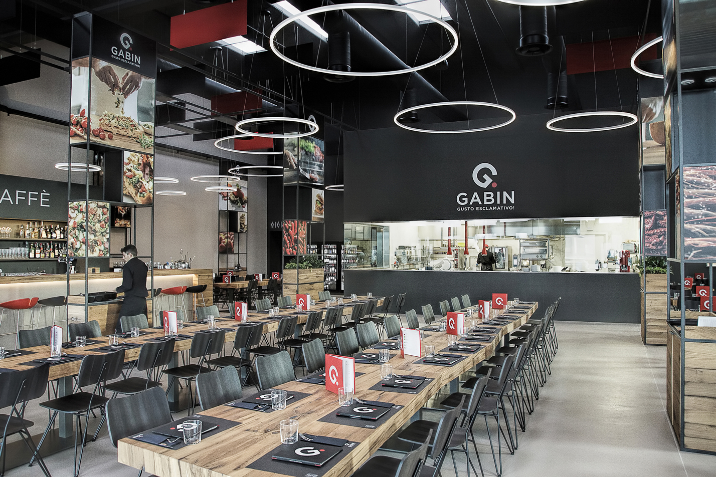 Vista prospettica della sala ristorante con diverse tipologie di tavoli e partizioni verticali che organizzano lo spazio.