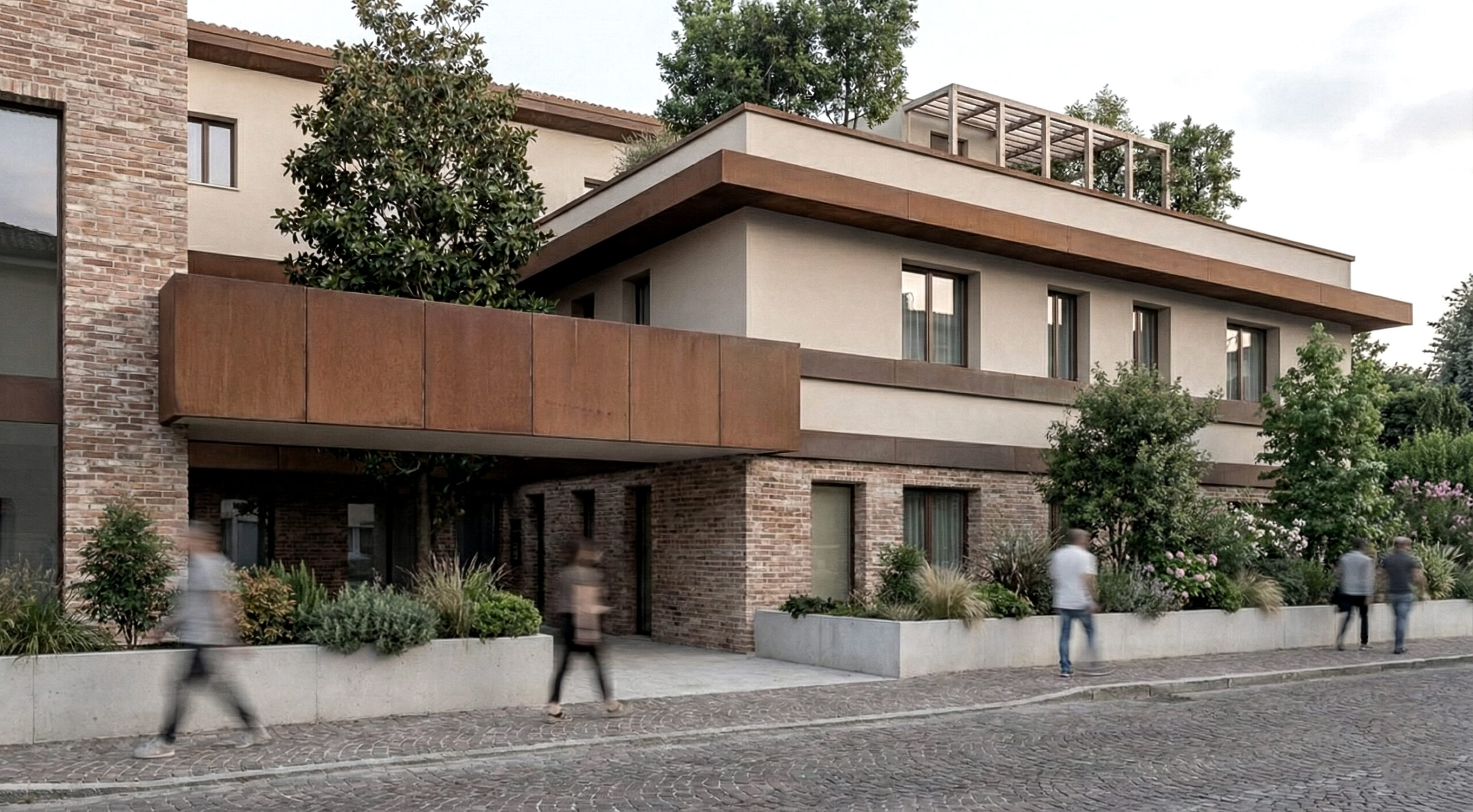 Vista ravvicinata dell’ingresso porticato del complesso residenziale a Verona: due volumi orizzontali con fasce in laterizio e coperture verdi, inseriti in un paesaggio curato.
